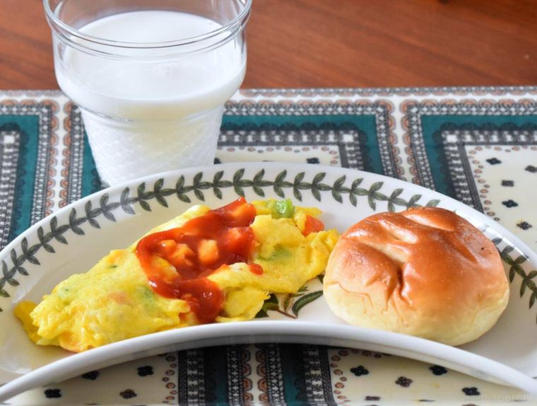 オムレツとパンをのせた皿、牛乳が入ったカップ
