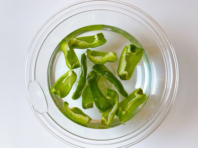 ボウルに入った水に浸したカットしたしわしわピーマン