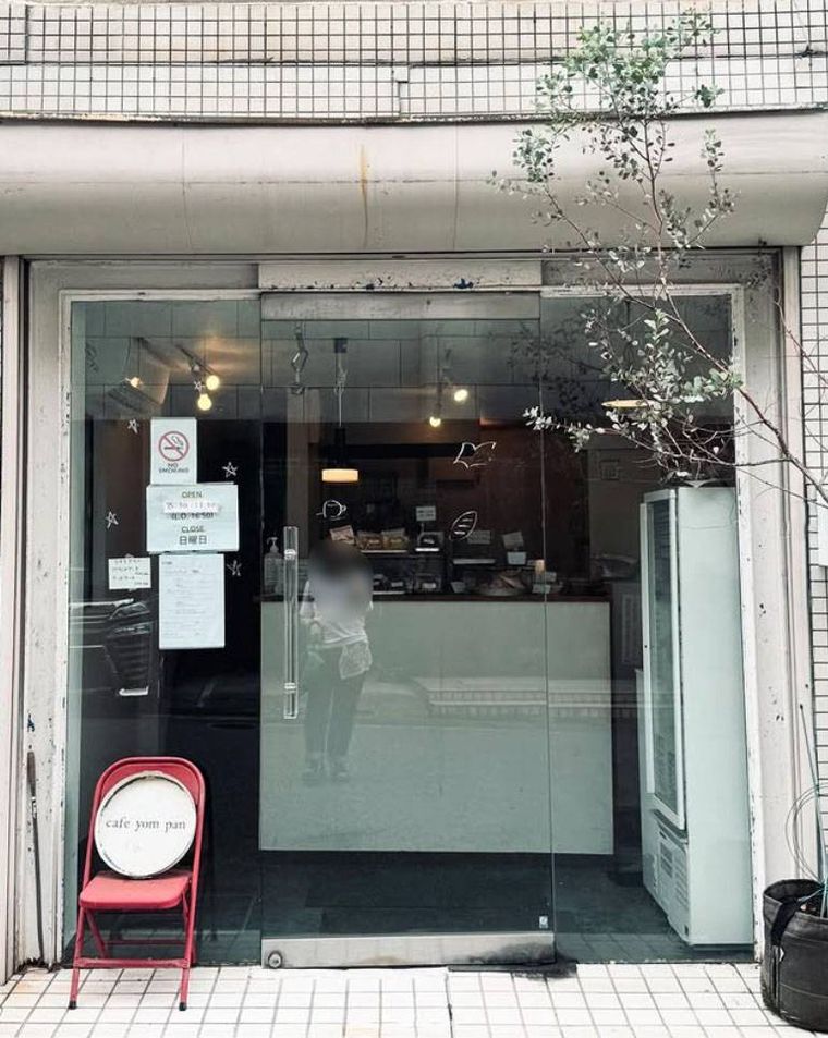 ガラス張りの入り口に赤い椅子が置かれたカフェ ヨムパンの外観