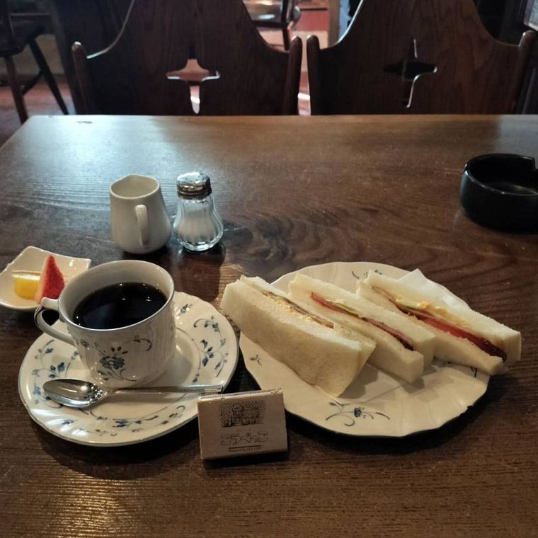 白にブルーの柄のお皿に盛られたサンドウイッチ ハーフベーコンとホットコーヒー