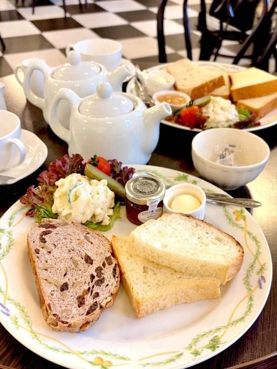 リーフのふちどりのある白いお皿に盛られたモーニングプレートとティーポット