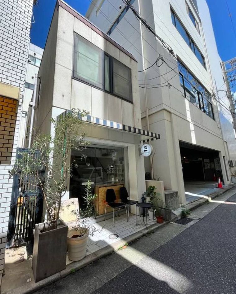 青と白の日よけがつきガラス扉のラウンドポイントカフェの外観