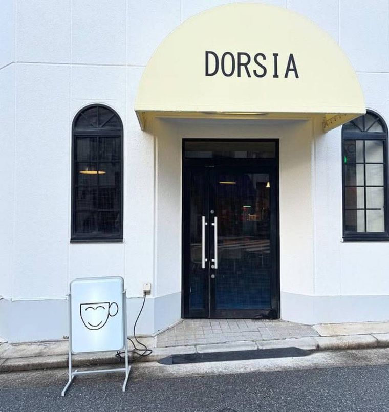 白い外壁にアーチ型の日よけがかかったドーシアの外観