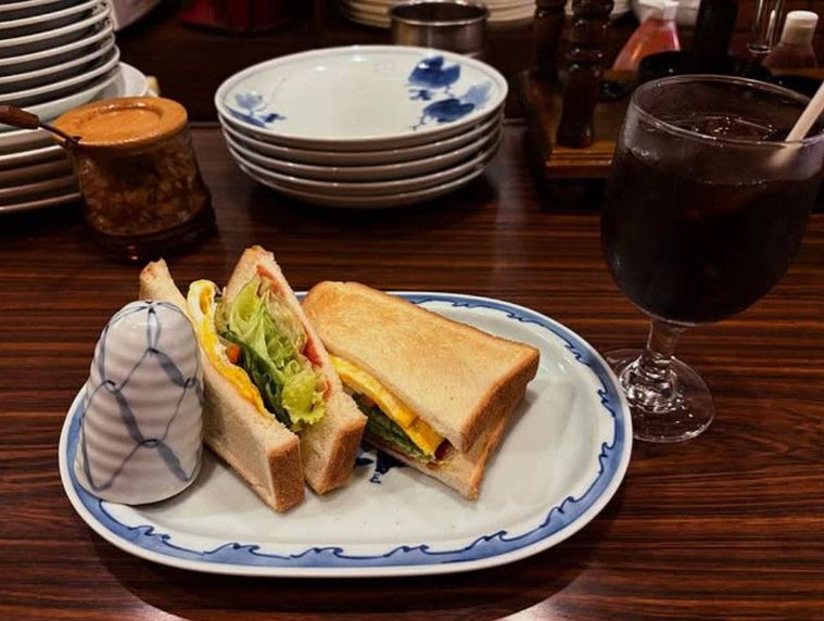 ブルーの縁の白いお皿に盛られたタマゴトーストとアイスコーヒー