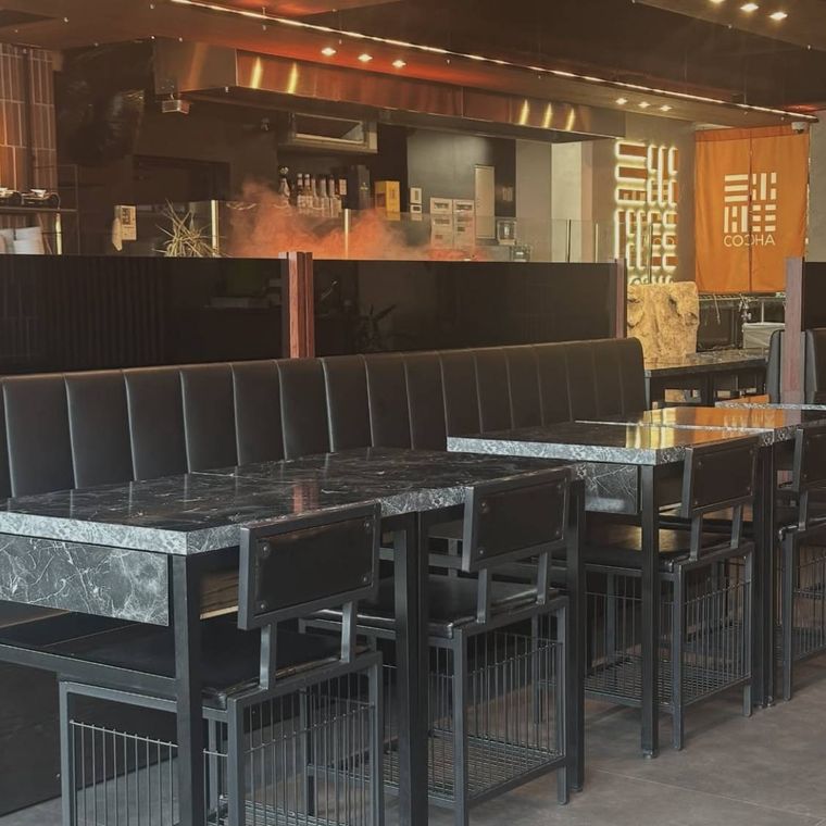 黒いテーブルと椅子が並んだコチャの店内