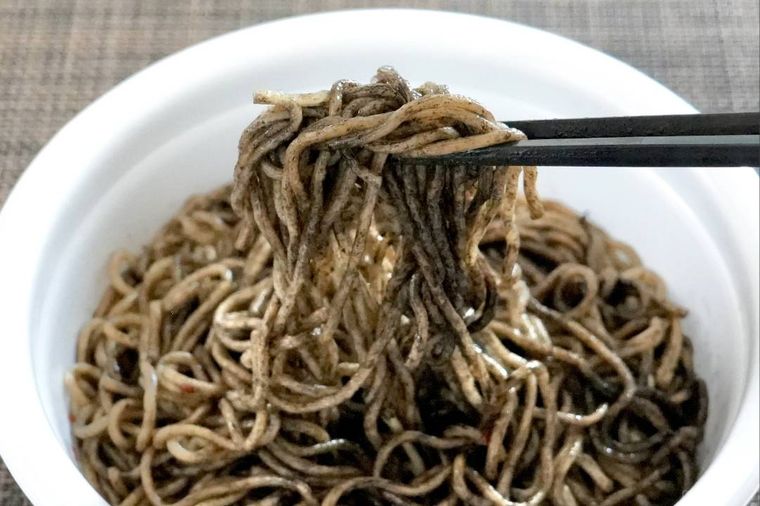 黒い箸でイカスミ焼きそばを食べる様子