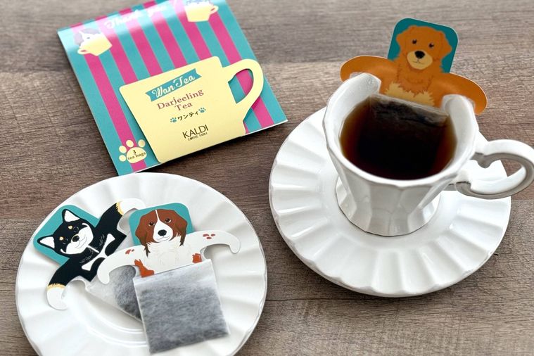 木のテーブルに紅茶が注がれた白いティーカップとワンティのティーバッグが置かれた白いお皿が置かれている