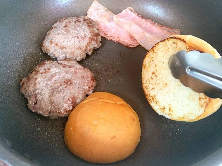 フライパンでパティと一緒にバンズの断面を焼く様子