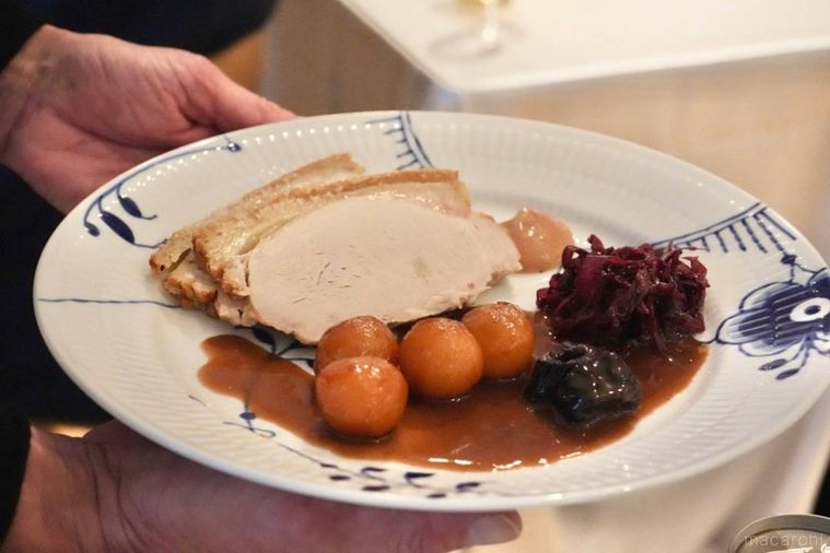 ローストポークとブラウンポテトがのった皿をサーブする手