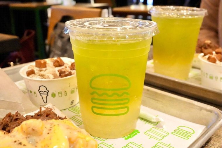 グリーンティーとレモネードのドリンクが入ったロゴ入りプラスチックカップ