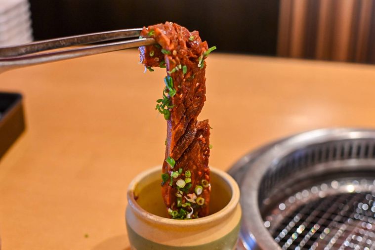 肉をトングでつかんでいるところ