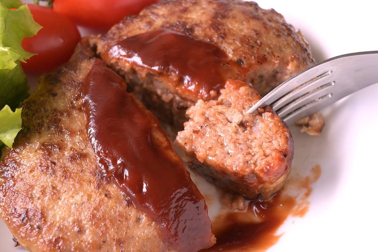 ひと口分にカットしたすりおろしじゃがいも入りのハンバーグにフォークを刺す様子