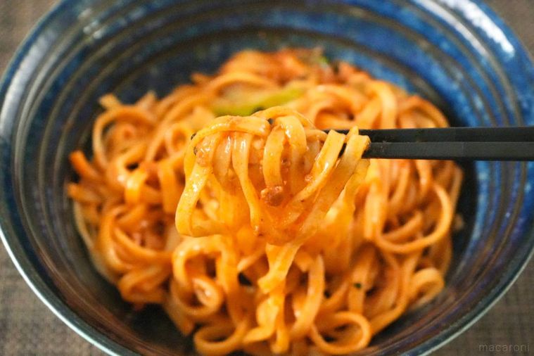 青い器に盛られた冷凍坦々麺を黒い箸で食べる様子