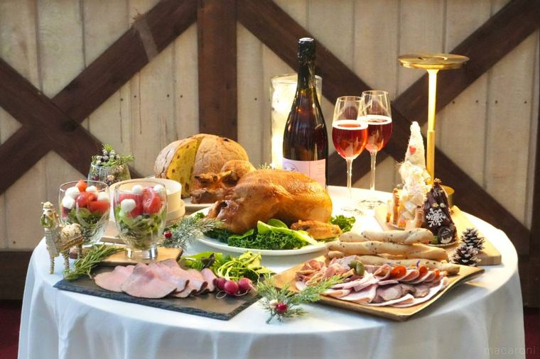 白いテーブルクロスの上に並べられたクリスマスチキンやオードブルやシャンパン