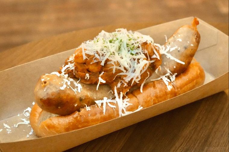 削りチーズとトマトソースがかかったホットドッグ