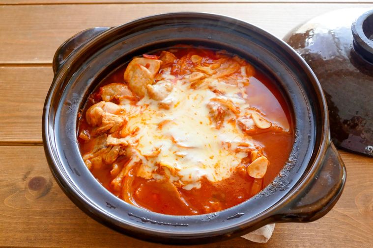 白菜たっぷりのトマト鍋が置かれている木製テーブル