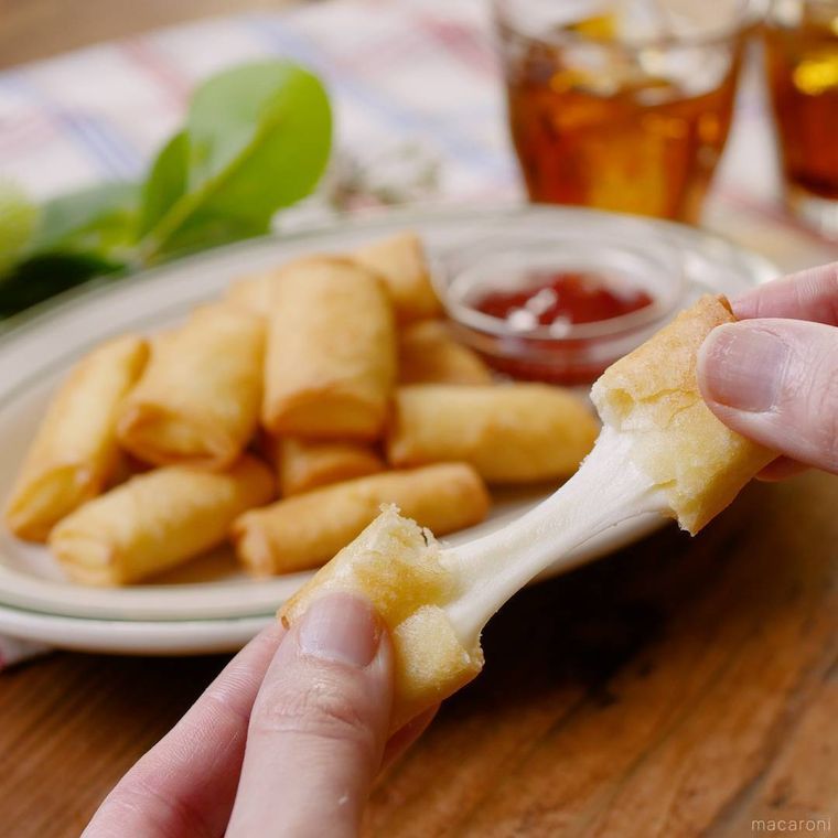 伸びるチーズ春巻きを手で割いている様子