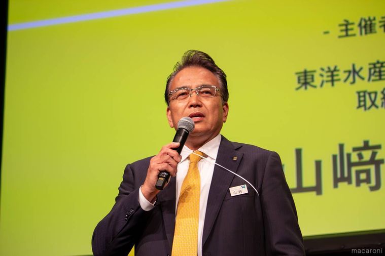 マイクを片手に挨拶する男性