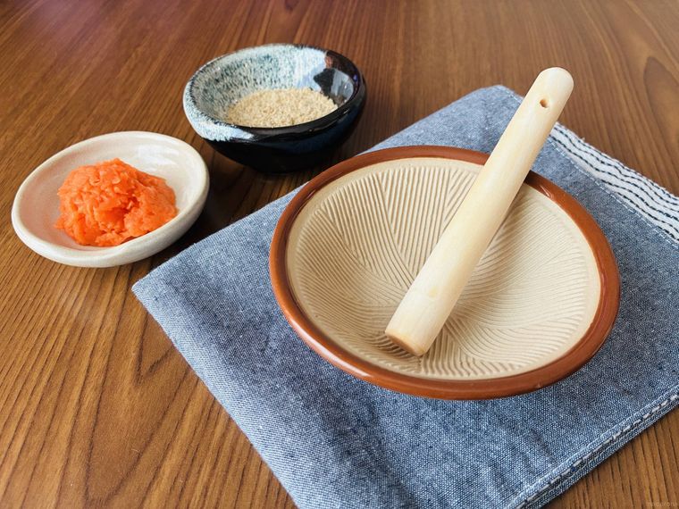 マットの上にあるミニすり鉢とすりこぎ、小皿に入ったにんじんとすりごま