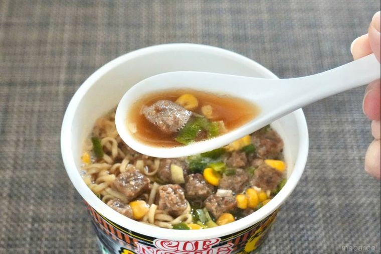 ガーリックペッパー味のカップヌードルのスープと具材を白いれんげですくう様子