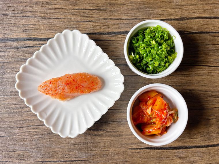 白色の皿に盛られた明太子、小口ねぎ、キムチ