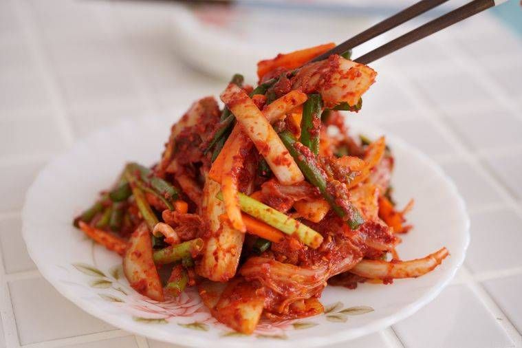 器に盛られたキムチを箸でつまんでいる様子