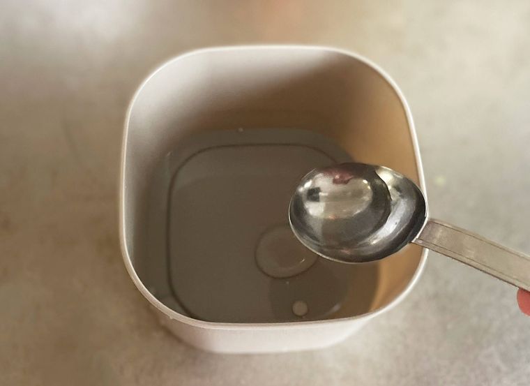 レンジ蒸し器にスプーンで水を入れている