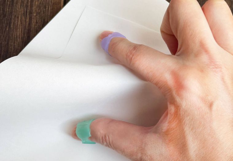 指サックで紙をめくっている