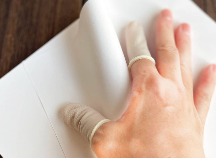 指サックで紙をめくっている