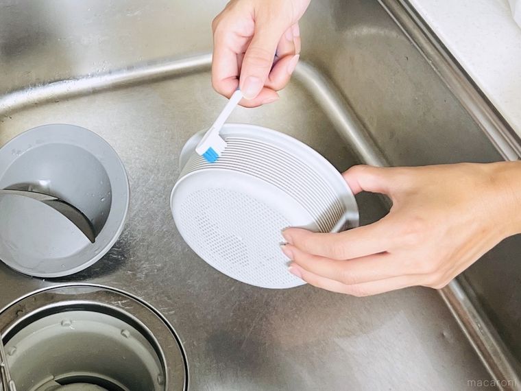 排水口のゴミ受けを古歯ブラシでこすっている様子