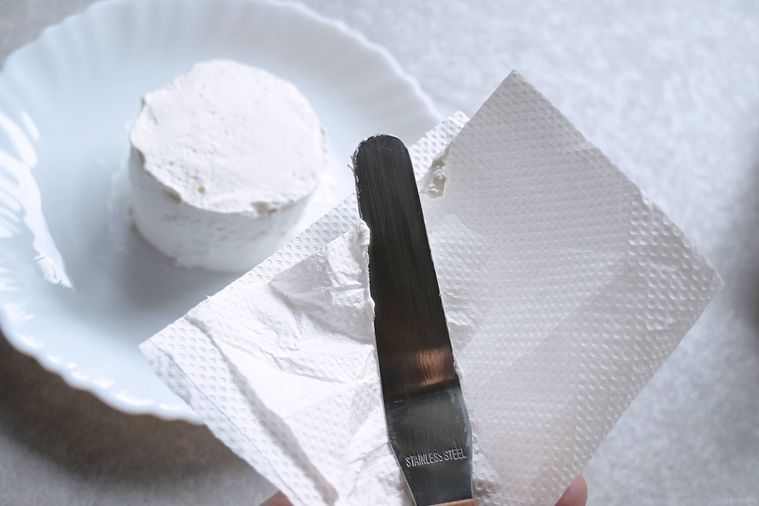 パレットナイフに付いたクリームをキッチンペーパーでふき取る様子