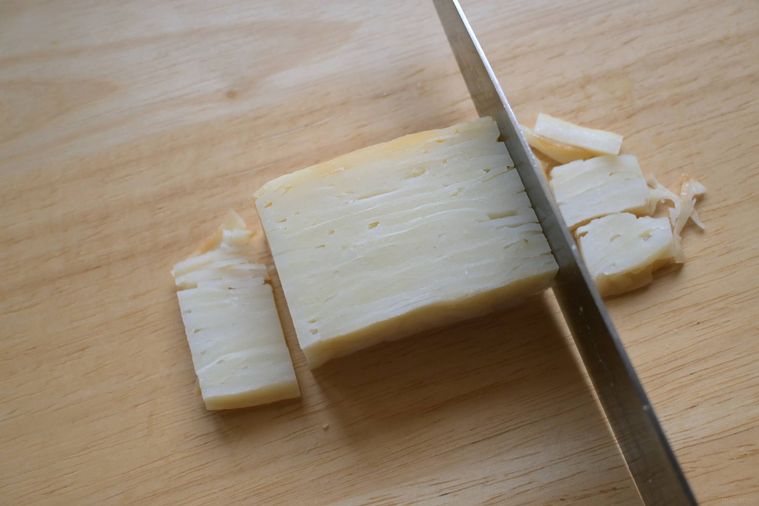 包丁でじゃがいもの重ね焼きの形を整える様子