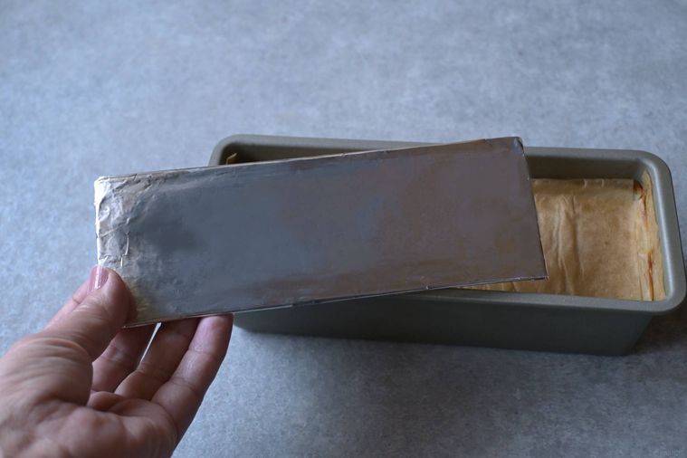 アルミホイルで覆った厚紙をパウンド型の上に重ねようとする様子