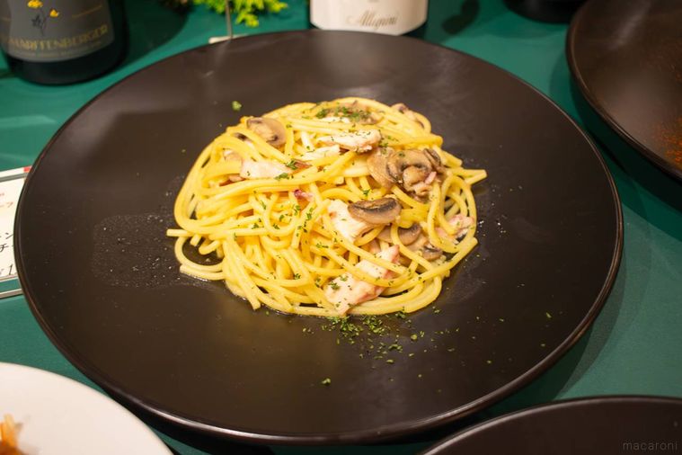 黒いお皿に盛り付けられたケンタッキー香るスモークチキンときのこのペペロンチーノ