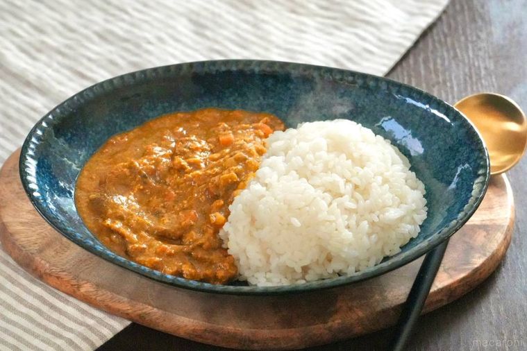 青い器に盛られた小松菜にんじんカレーと黒色と金色のスプーン
