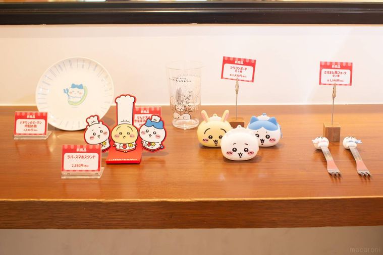 ちいかわレストランの討伐フェア限定グッズが木製のカウンターに並んでいる