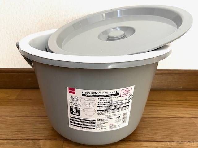 床に置かれている蓋とカゴ付きのバケツ