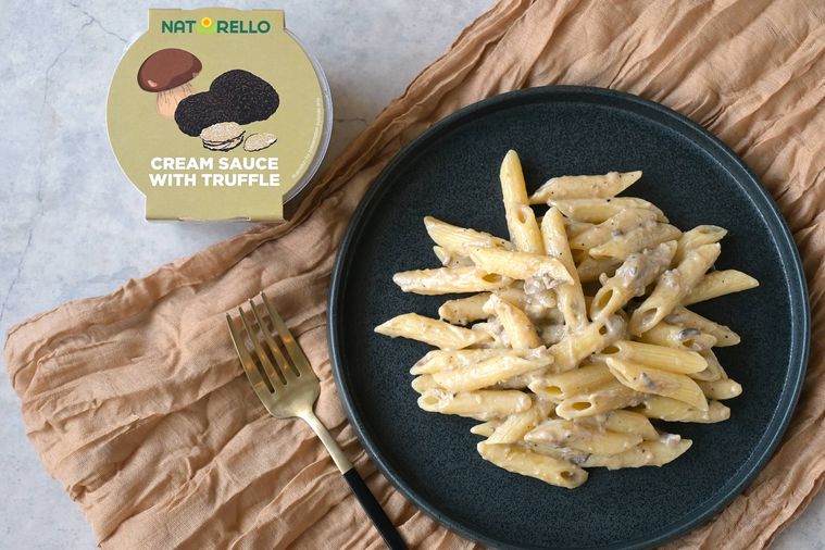 トリュフ入りクリームソースを絡めたペンネが黒い丸皿に盛り付けられている