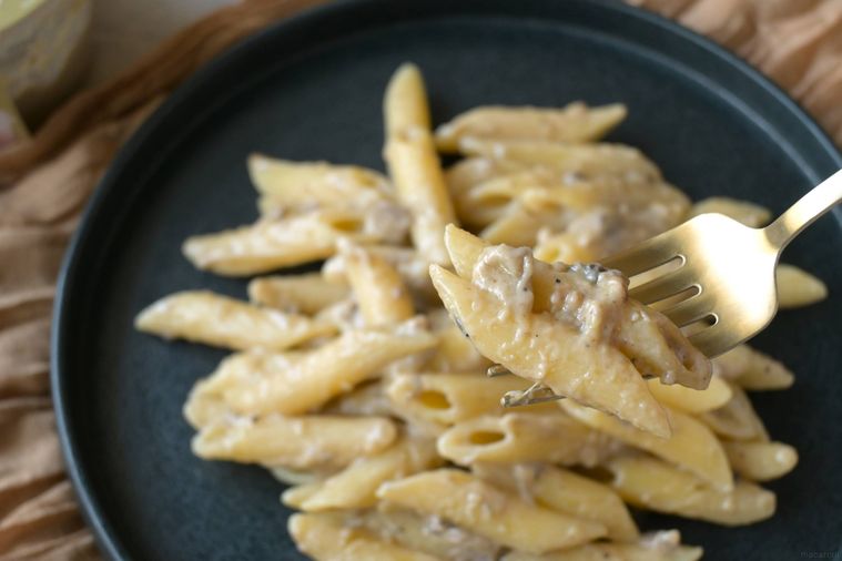 トリュフ入りクリームソースを絡めたペンネをフォークですくう様子