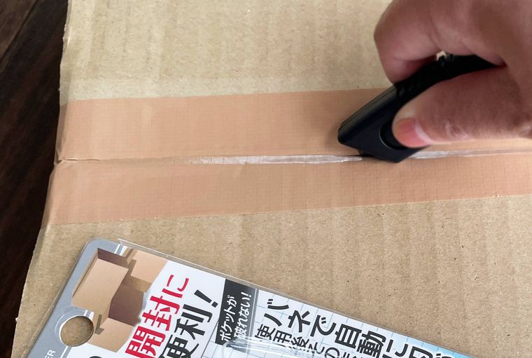 カッターを使って段ボールを開封している写真