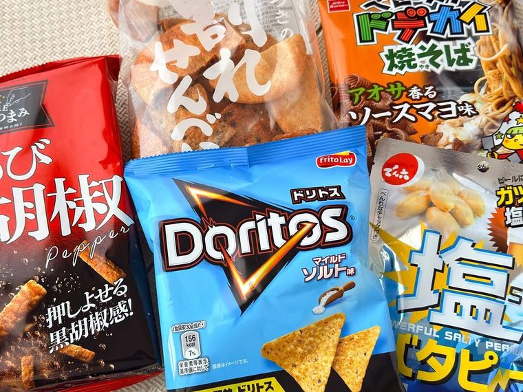 詰めすぎチャレンジ あふれそうなハッピー 2025福袋のおせんべいやチップスなどのパッケージが並べられている様子