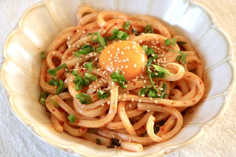 うどんにたれを絡めて卵黄をのせた様子