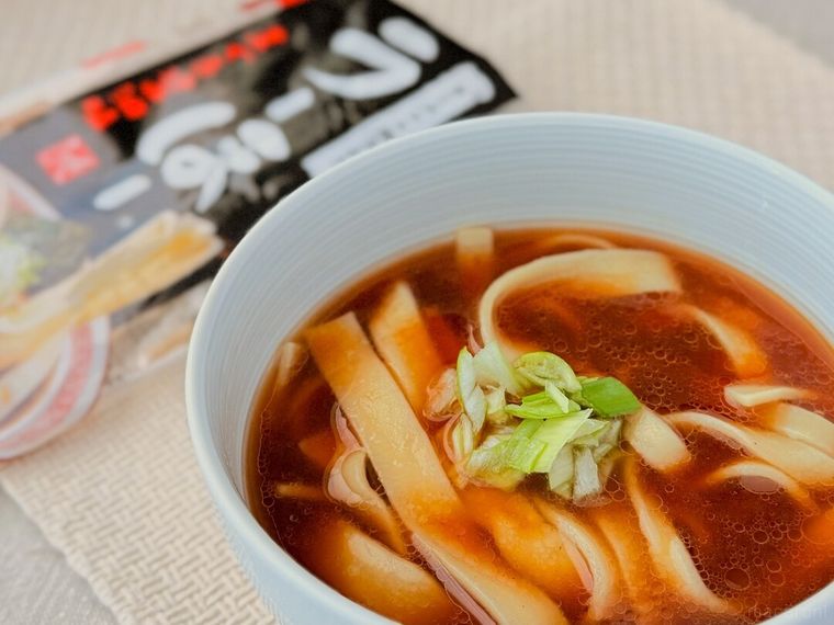 トッピングを盛り付けたラーほー まぐろ醤油味とパッケージが並んでいる様子