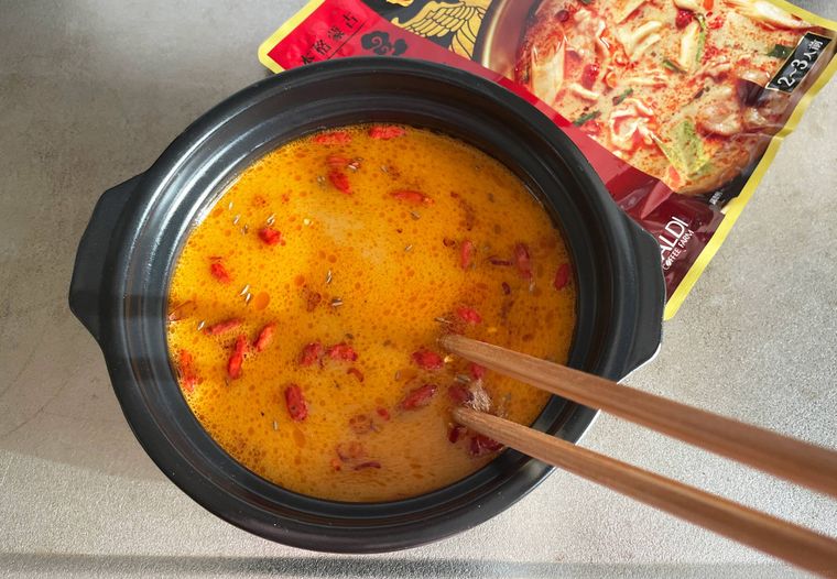 土鍋に入れた火鍋の素を箸でかき混ぜているところ