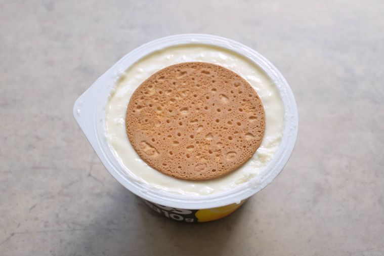 オイコスの容器に入ったチーズケーキ生地にビスケットをのせた様子