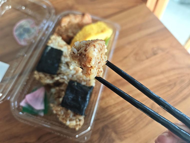 鶏かしわおにぎり盛り合わせに入っているおにぎりを箸で持ち上げている様子