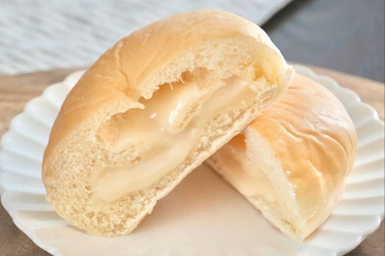 木のカッティングボードと白い皿にのったミルククリームパンの断面