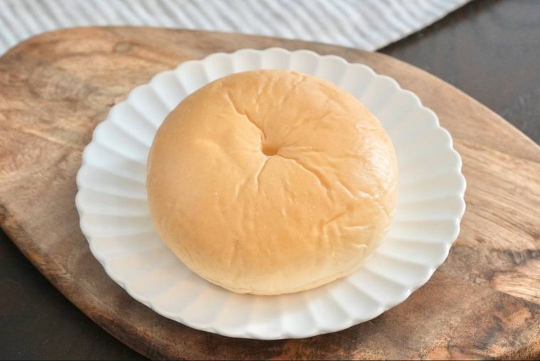 木のカッティングボードと白い皿にのったミルククリームパン