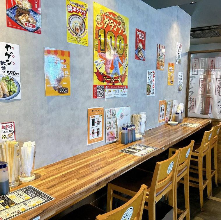 壁にポスターが貼られた餃子のかっちゃん 難波道頓堀店のカウンター席