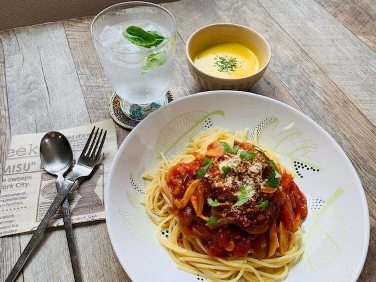 イタリアンパセリとチーズをトッピングした、なすのトマトソースパスタの白い皿